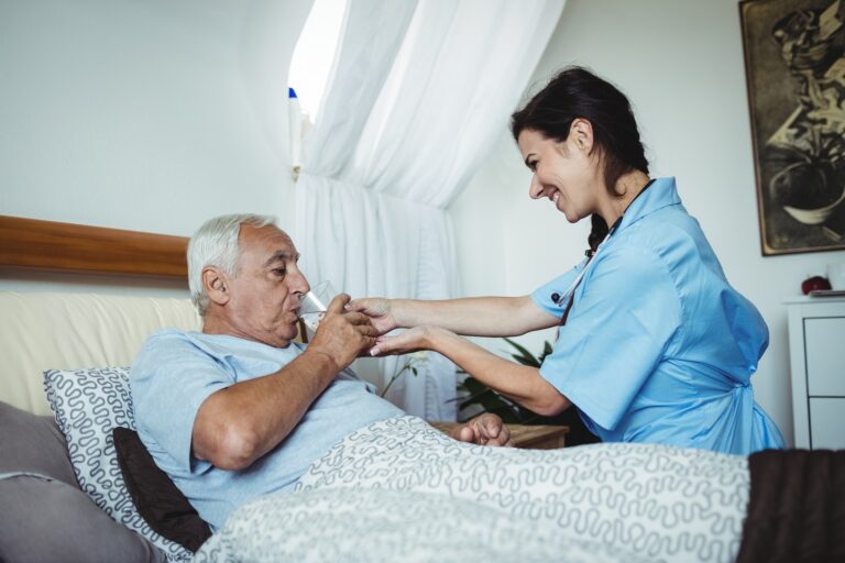 Nurse giving a glass of water to senior man at home